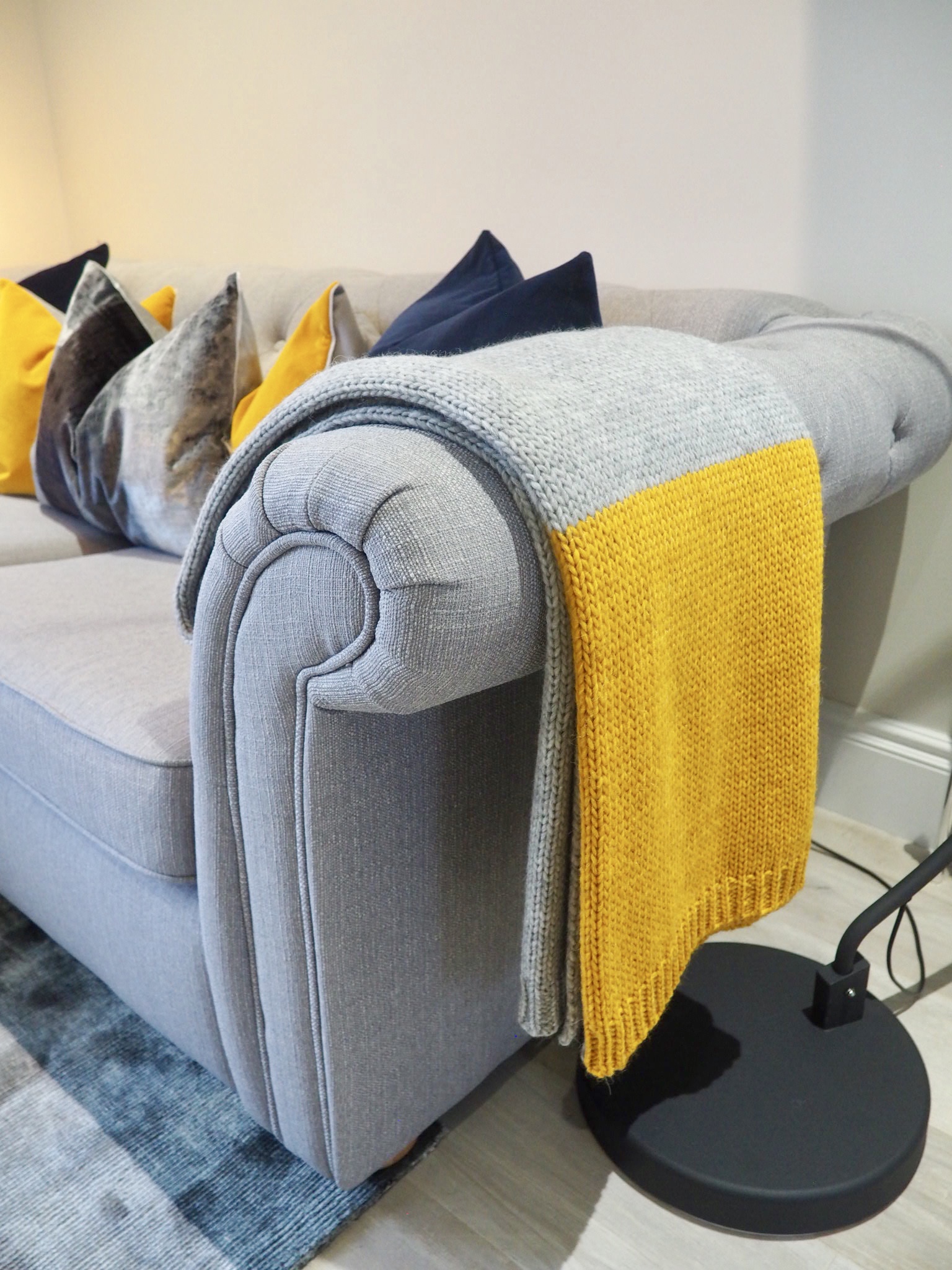 Grey chesterfield sofa with grey and ochre Alpaca throw, and a slection of cushions in navy, ochre and grey velvets