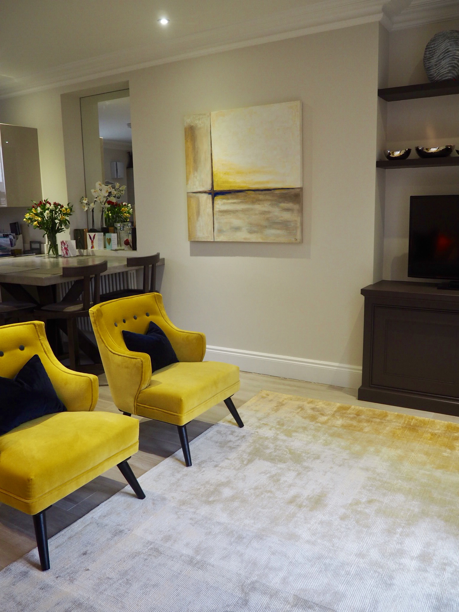 Living room with ombré grey and mustard rug, two mustard coloured chairs and cushions ranging through navy, ochre and grey, with a faux alligator tray.