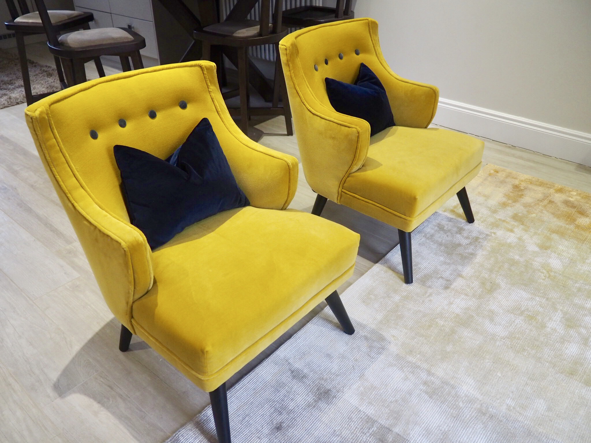 Navy velvet cushions sitting on top of two mustard velvet chairs from Atkin and Thyme