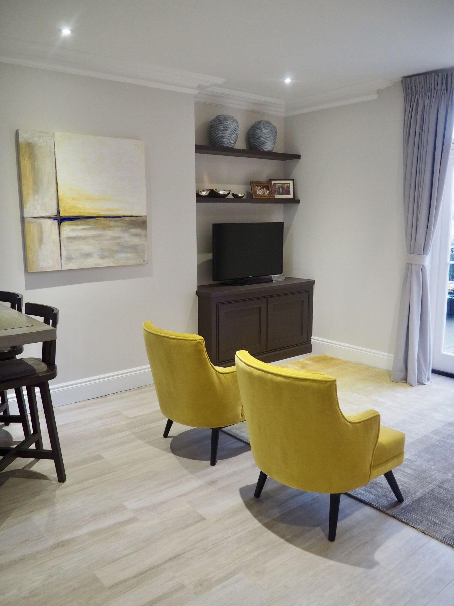 Living room with ombré grey and mustard rug, two mustard coloured chairs and cushions ranging through navy, ochre and grey, with a faux alligator tray.