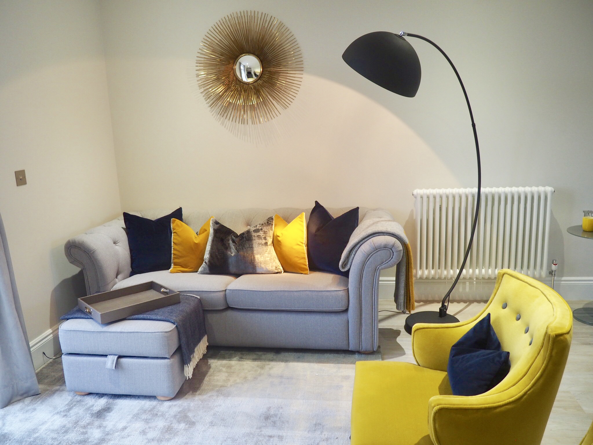 Living room with ombré grey and mustard rug, two mustard coloured chairs and cushions ranging through navy, ochre and grey, with a faux alligator tray.