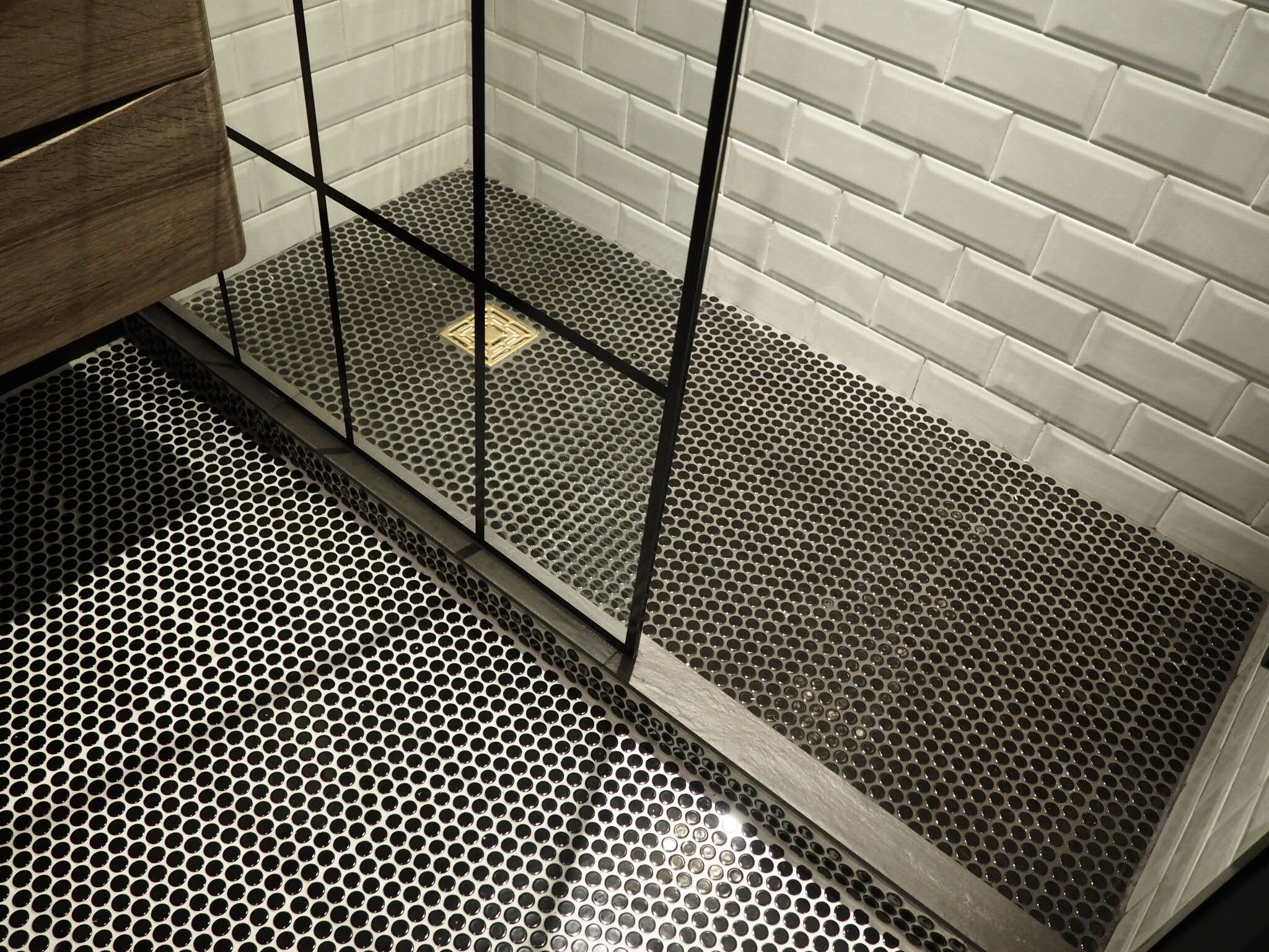 Shower floor using black polished penny tiles with a slate step, white grout on the main floor and black grout in the shower. Crittal style shower screen just seen