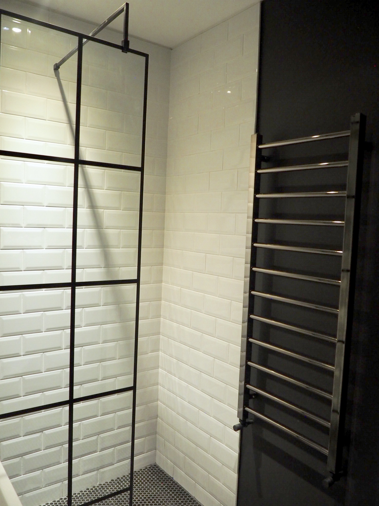 Crittal style shower screen housing the white subway tiles and next to the Farrow and a Ball offblack wall with anthracite towel radiator